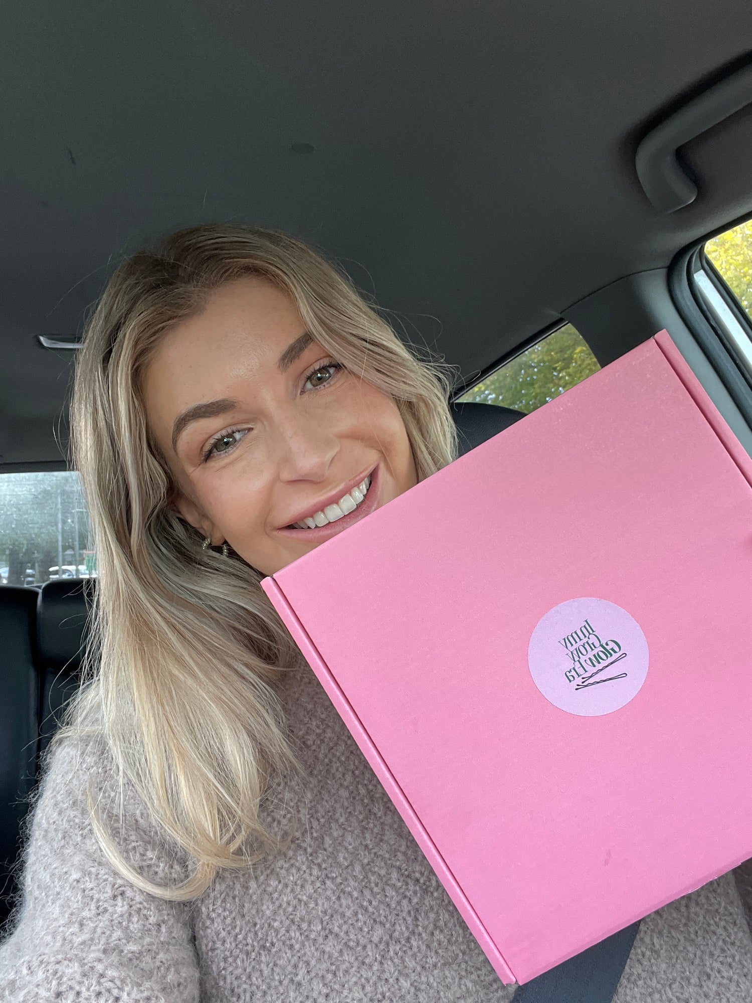 Girl holding Grow Glow hair care kit, featuring pre-wash oil and scalp massager for healthier hair.